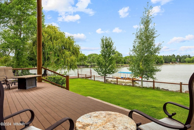 wooden terrace with a water view, a lawn, and fence