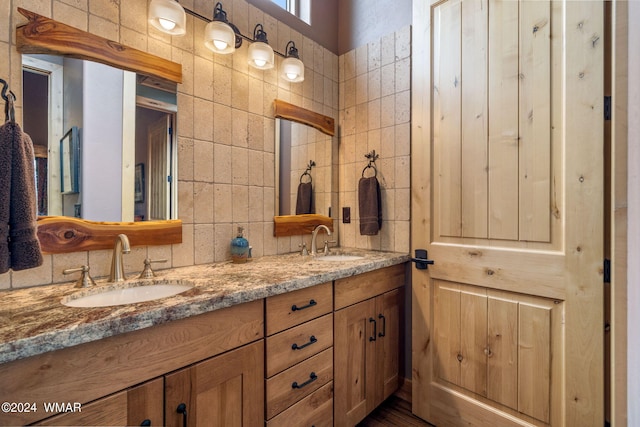 bathroom with tile walls, double vanity, and a sink