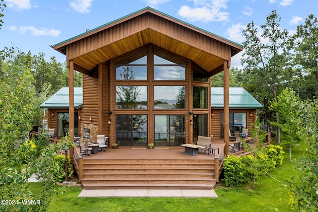 back of property featuring log veneer siding, a yard, stone siding, a deck, and metal roof