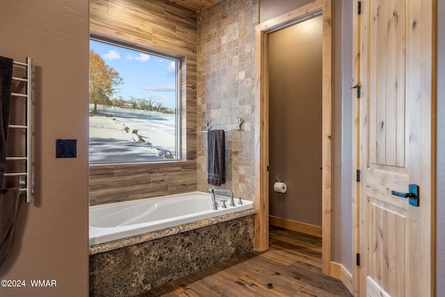 full bath with a bath, baseboards, and wood finished floors