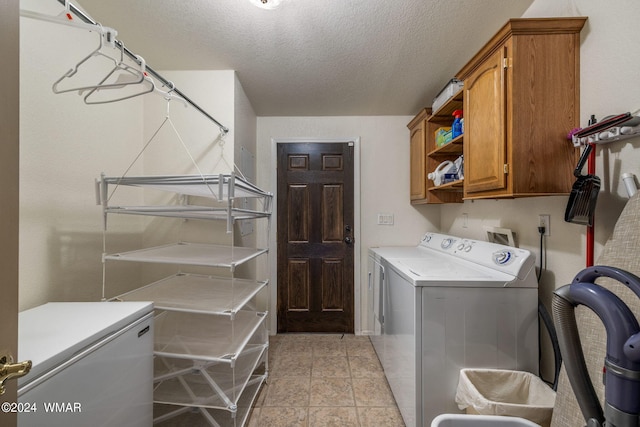 laundry area with light tile patterned flooring, washing machine and dryer, cabinet space, and a textured ceiling