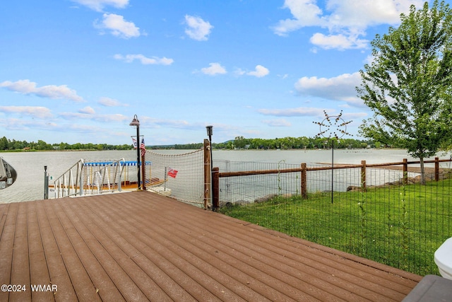 view of dock with fence, a yard, and a water view