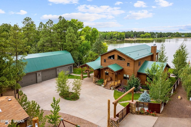 view of front of house featuring a water view, a chimney, metal roof, a garage, and driveway