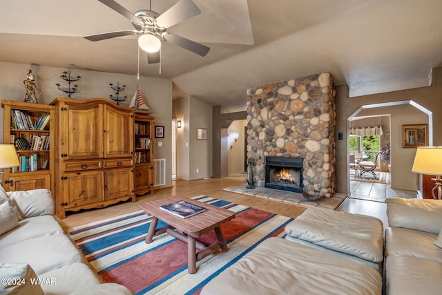 living area with a ceiling fan, visible vents, light wood-style flooring, arched walkways, and vaulted ceiling