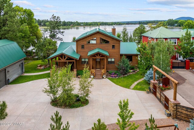 cabin featuring metal roof, a water view, a chimney, and a front lawn