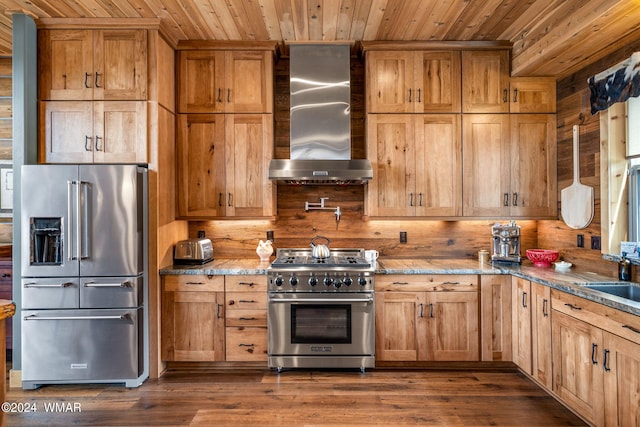 kitchen featuring premium appliances, dark wood finished floors, wooden ceiling, wall chimney range hood, and light stone countertops