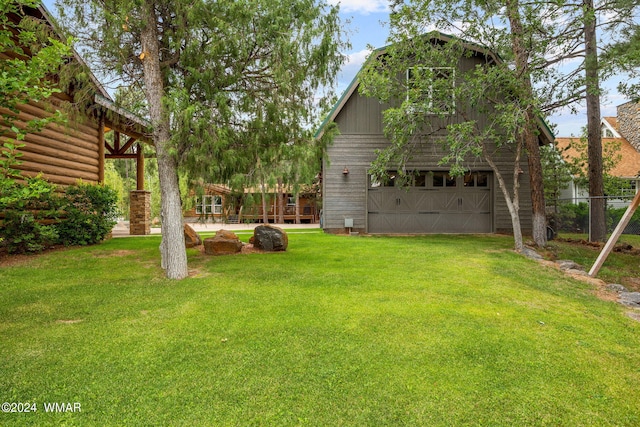 view of yard with a garage, an outbuilding, a barn, and fence