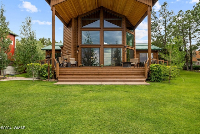 back of property with metal roof, a lawn, a deck, and faux log siding