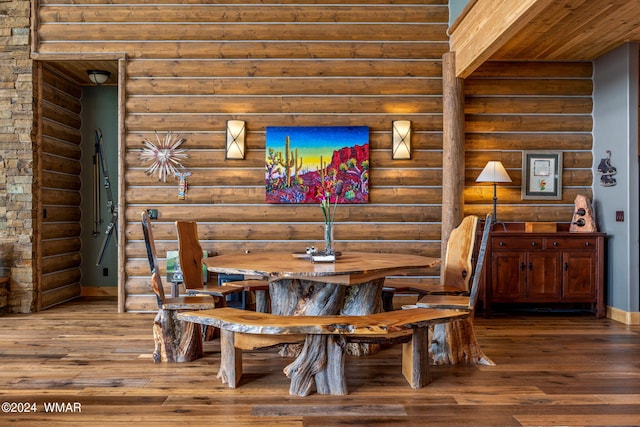 dining space featuring log walls, baseboards, and wood finished floors