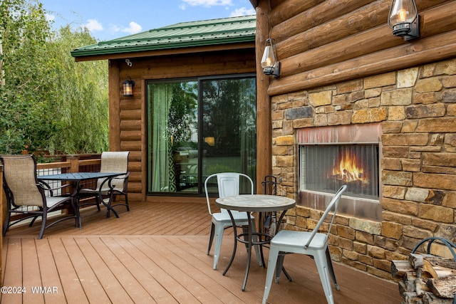 deck featuring outdoor dining area and an outdoor stone fireplace