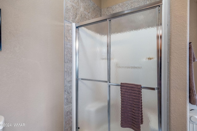 bathroom featuring a shower stall and a textured wall