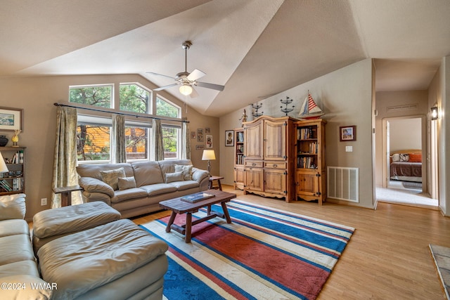 living area featuring lofted ceiling, visible vents, light wood finished floors, and ceiling fan