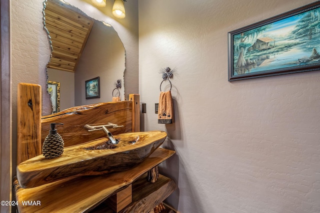 bathroom featuring lofted ceiling and a textured wall