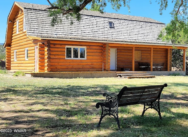 back of property with a yard, log exterior, and a gambrel roof