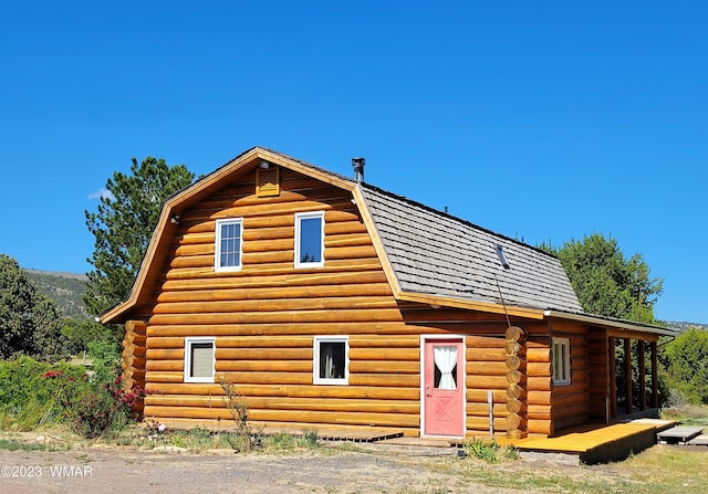 exterior space featuring a barn, a gambrel roof, and log siding