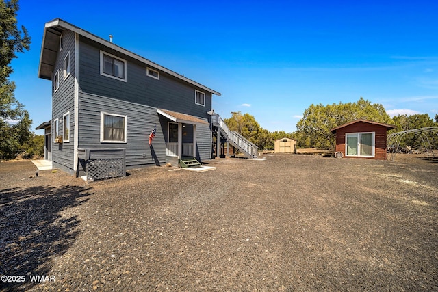 rear view of house with a storage unit, entry steps, and an outbuilding