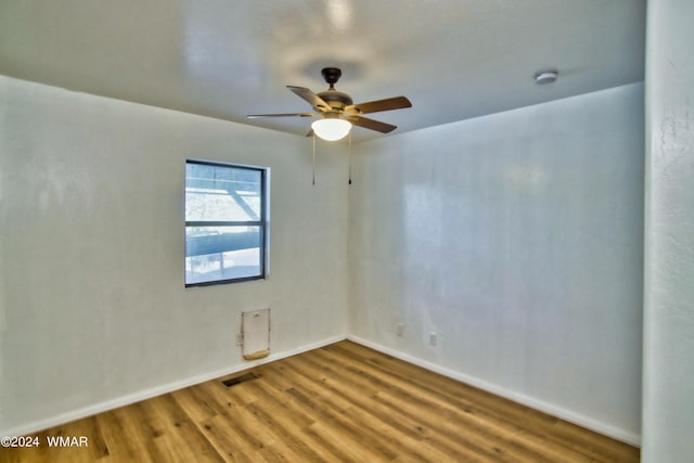 unfurnished room featuring baseboards, visible vents, wood finished floors, and a ceiling fan