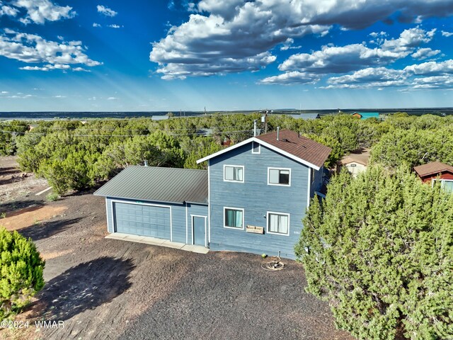 8286 Pinon Dr, Show Low, AZ 85901 - view of front of home with a garage, driveway, metal roof, and a forest view