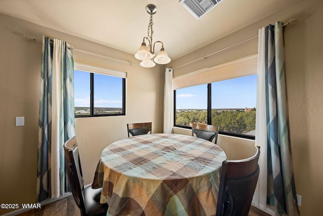 dining area with a chandelier, visible vents, wood finished floors, and a wealth of natural light