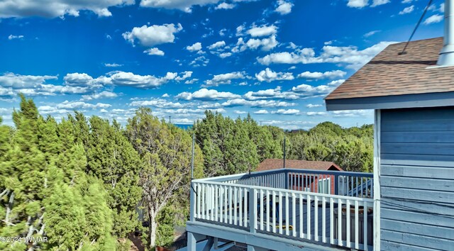 view of wooden balcony with a deck and a forest view