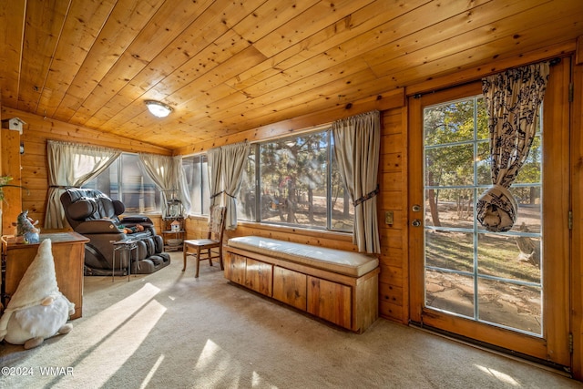 sitting room with lofted ceiling, wooden ceiling, light colored carpet, and wooden walls