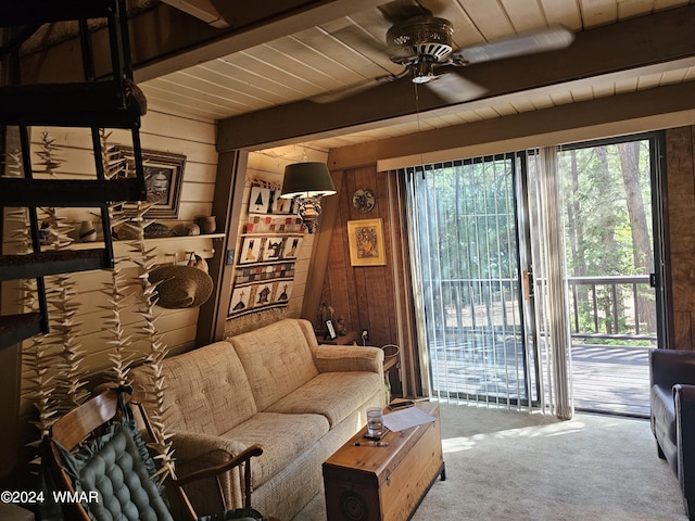 carpeted living area with wood walls, wooden ceiling, beam ceiling, and a ceiling fan