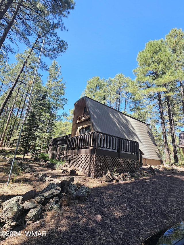 view of side of home with metal roof, a wooden deck, and a gambrel roof