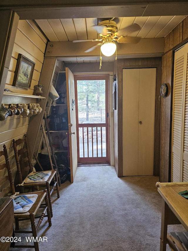 carpeted foyer featuring ceiling fan and wooden walls