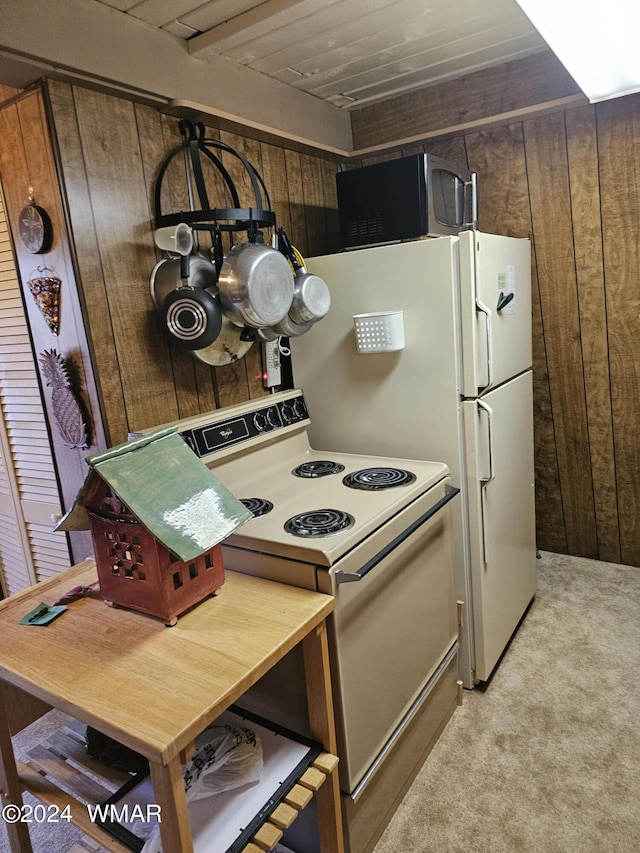 kitchen with black microwave, light colored carpet, white electric stove, and wood walls