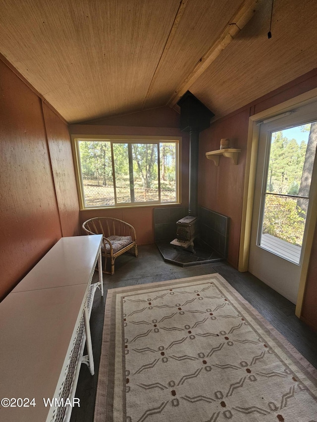 unfurnished sunroom with a wood stove, wood ceiling, and lofted ceiling