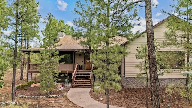 view of front of house featuring a deck, a chimney, roof with shingles, and stairway