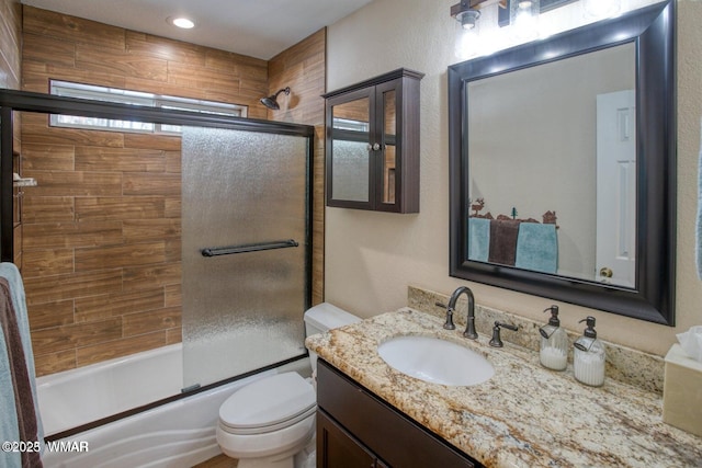 bathroom featuring toilet, shower / bath combination with glass door, and vanity