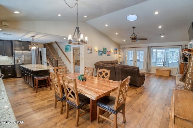 dining room featuring light wood-style floors, ceiling fan with notable chandelier, stairs, and lofted ceiling