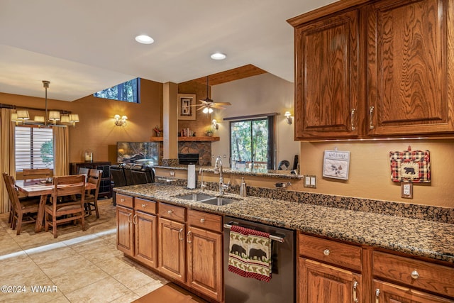 kitchen with dark stone counters, stainless steel dishwasher, brown cabinetry, and a sink