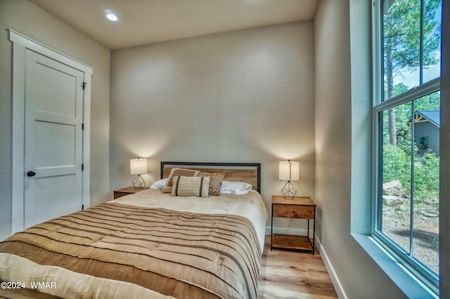 bedroom with recessed lighting, multiple windows, light wood-style flooring, and baseboards