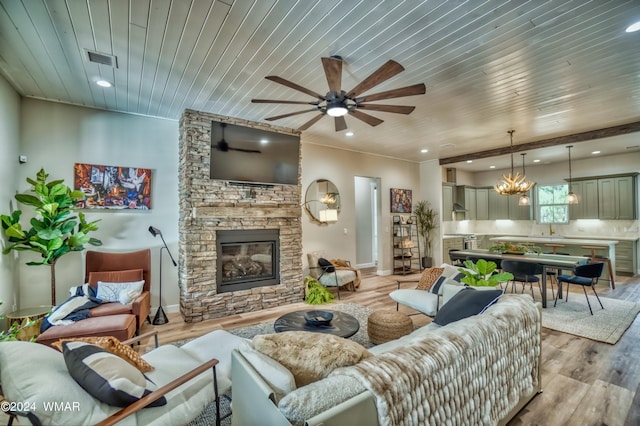 living room featuring light wood-type flooring, wooden ceiling, a stone fireplace, and recessed lighting