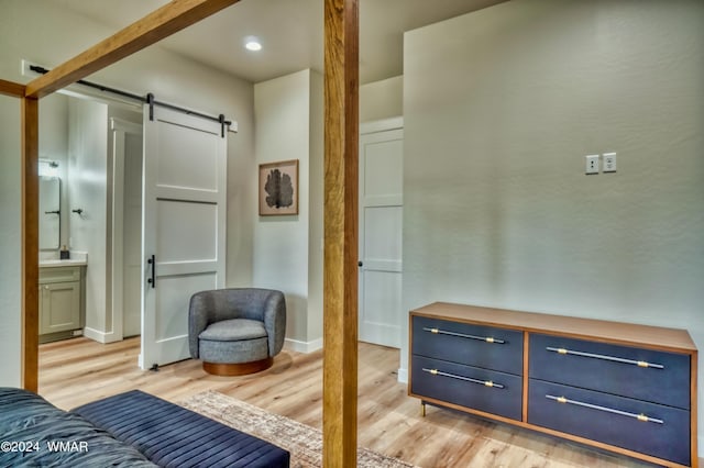 interior space with baseboards, a barn door, connected bathroom, and light wood-style floors