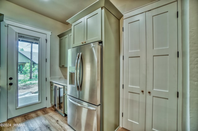 kitchen featuring beverage cooler, light countertops, light wood-style floors, and stainless steel fridge with ice dispenser