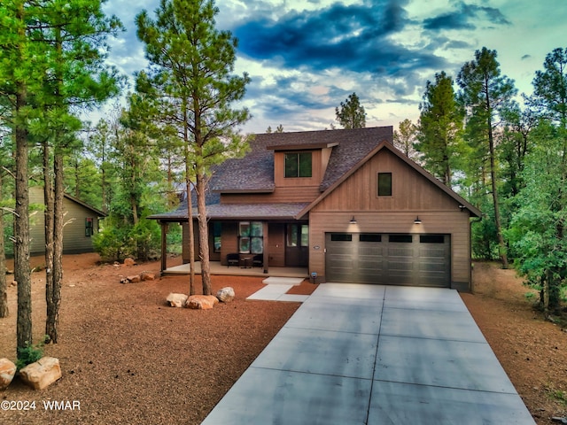 view of front of property with a garage, covered porch, roof with shingles, and driveway