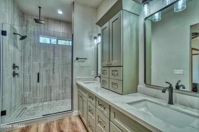 full bath with double vanity, wood finished floors, a sink, and a shower stall