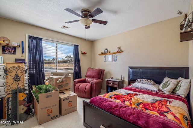 bedroom featuring a ceiling fan, visible vents, light carpet, and a textured ceiling