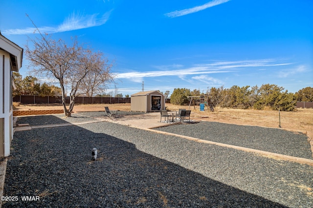 view of yard with a patio, playground community, a shed, a fenced backyard, and an outdoor structure