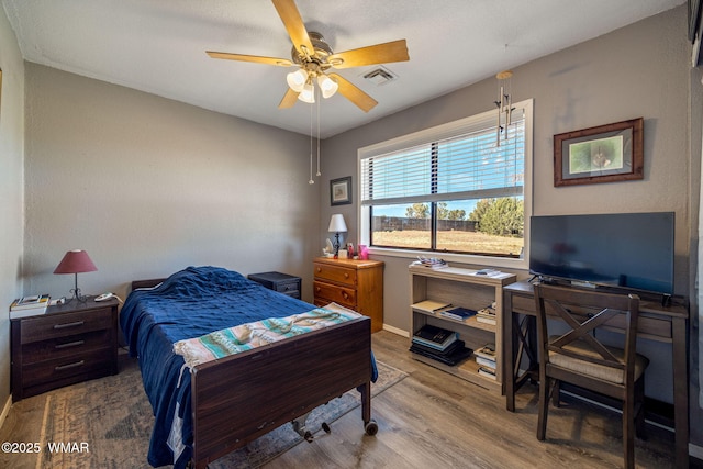 bedroom with baseboards, ceiling fan, visible vents, and wood finished floors