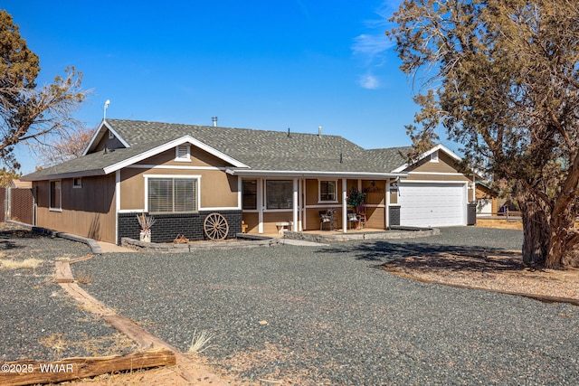 view of front of home featuring a porch, brick siding, a shingled roof, and a garage