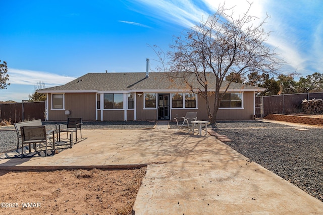 rear view of house featuring a shingled roof, fence, and a patio