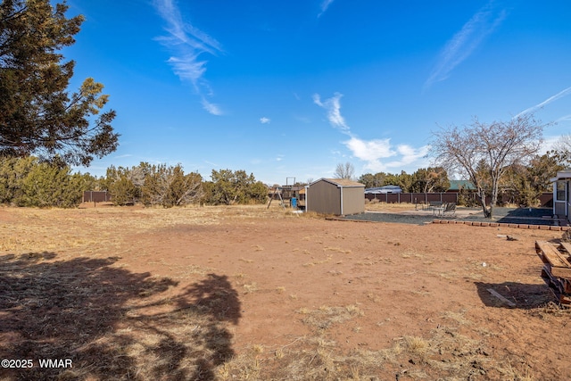 view of yard featuring an outbuilding, fence, and a storage shed