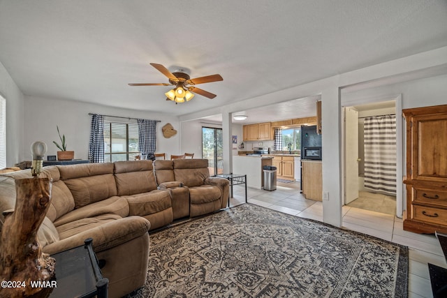 living area featuring a ceiling fan, a textured ceiling, and light tile patterned floors