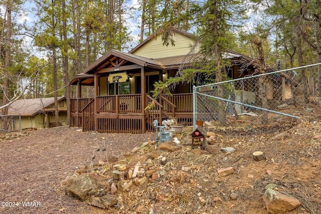 view of front facade featuring covered porch, fence, and metal roof