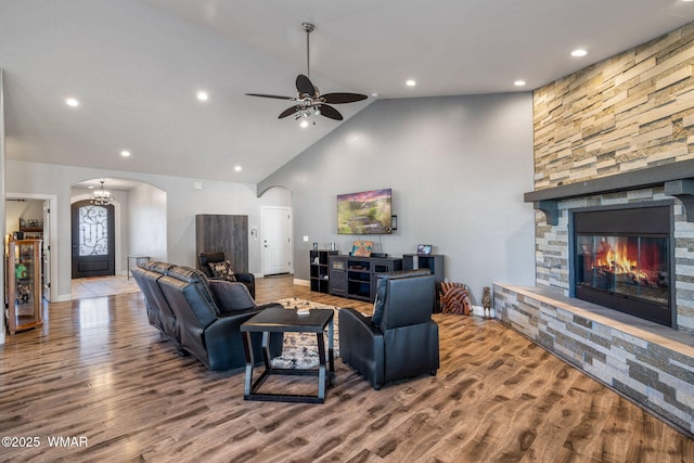 living room with baseboards, ceiling fan, a fireplace, wood finished floors, and arched walkways