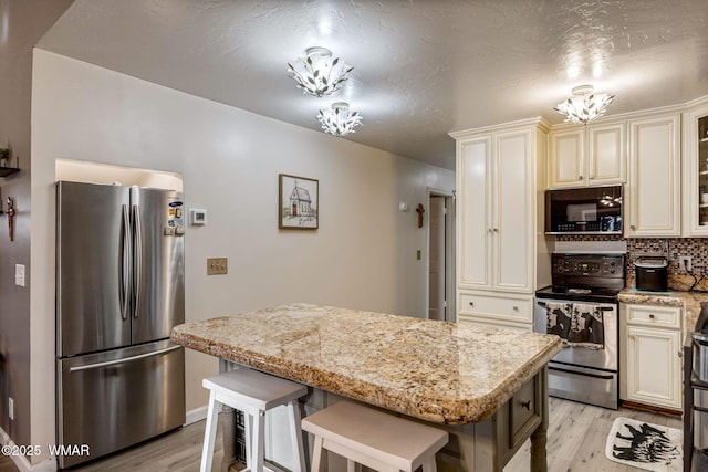 2331 W Rogers Loop, Show Low, AZ 85901 - kitchen with freestanding refrigerator, range with electric cooktop, black microwave, cream cabinetry, and light wood finished floors